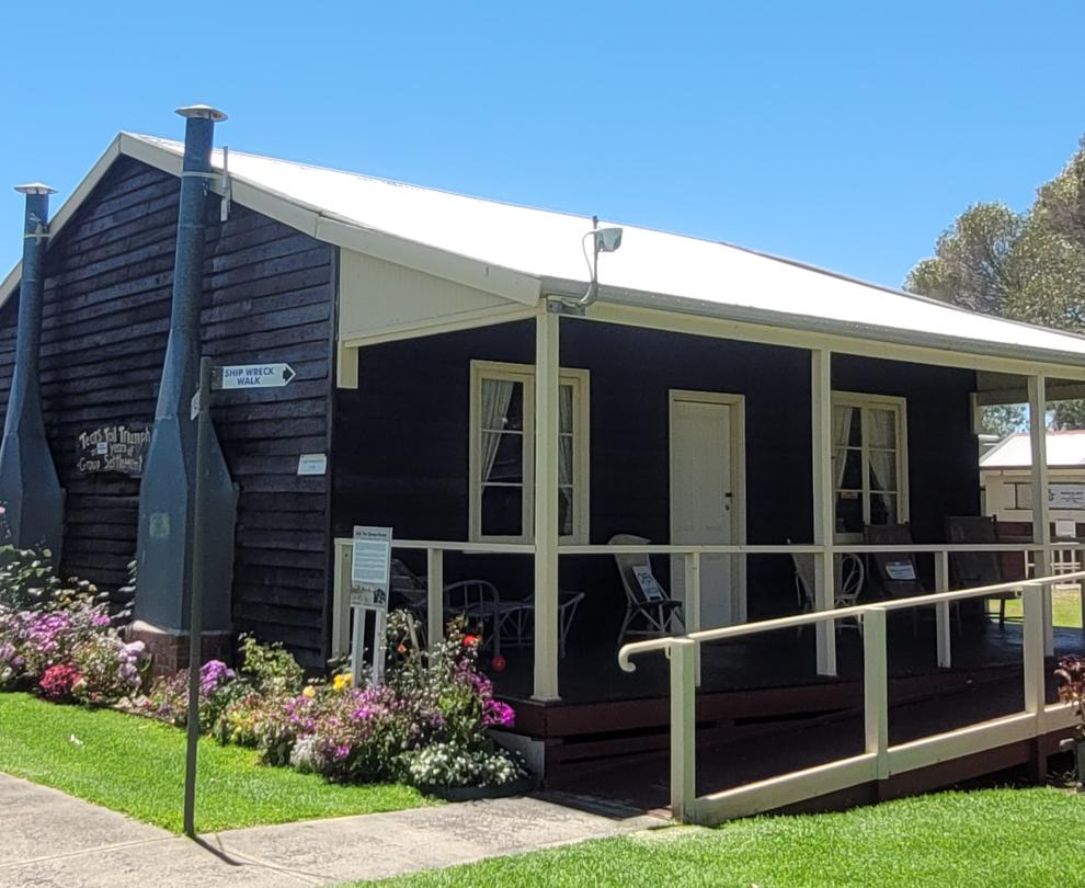 A wooden building next to flowers and grass